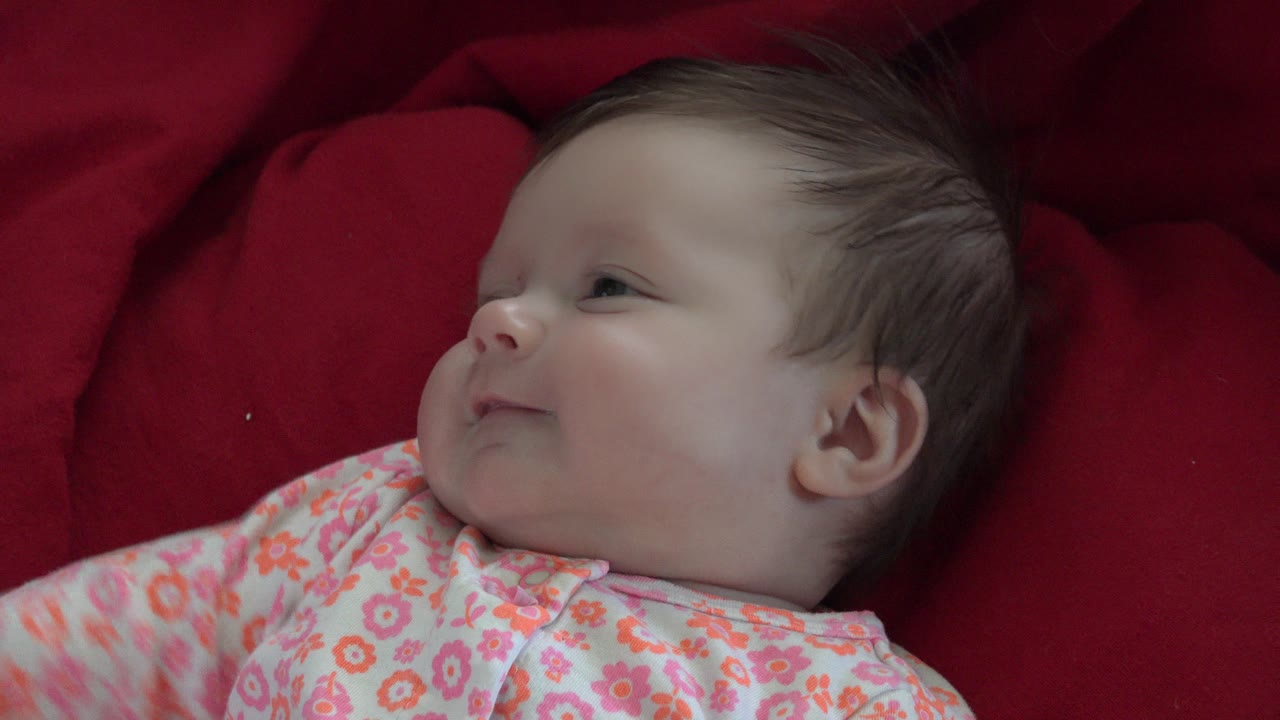 Baby looking to the side on a red blanket.