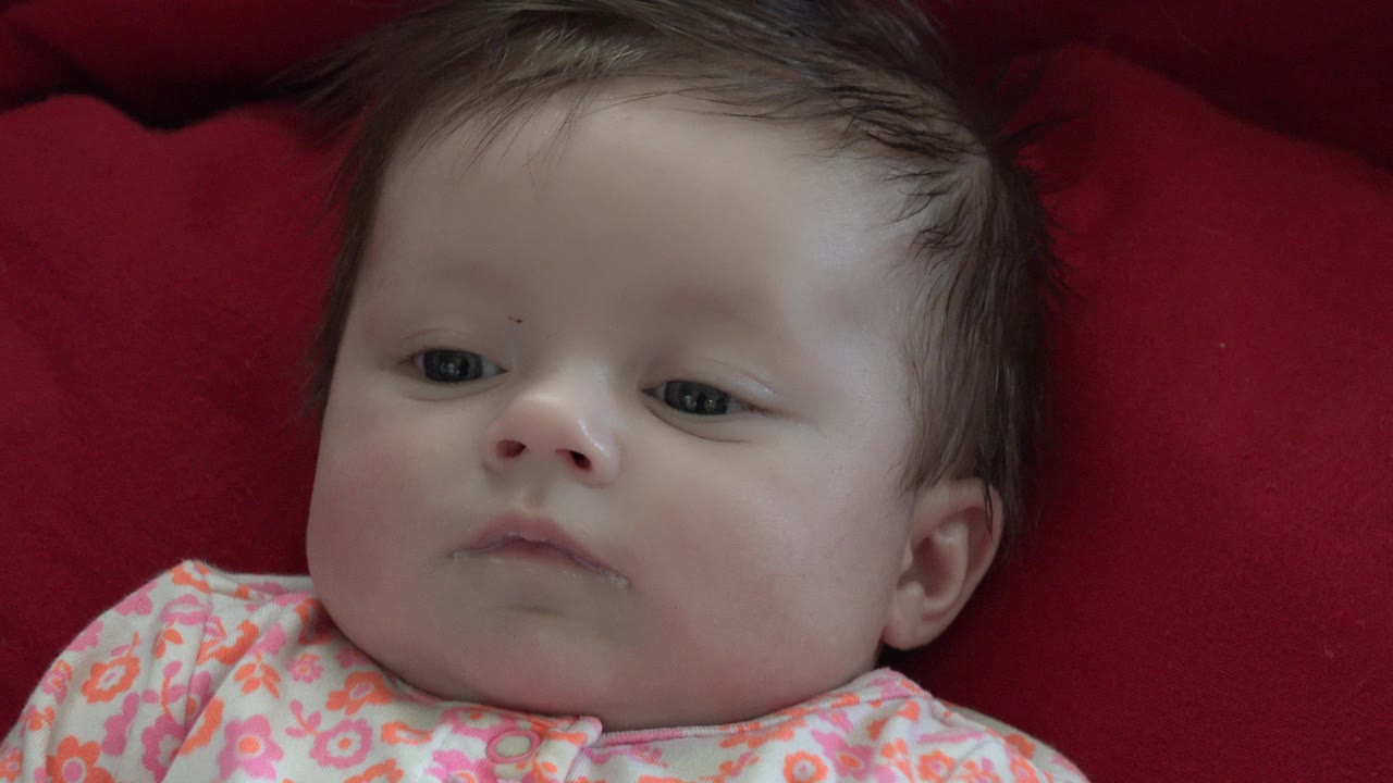 Baby close-up with red blanket behind the head.