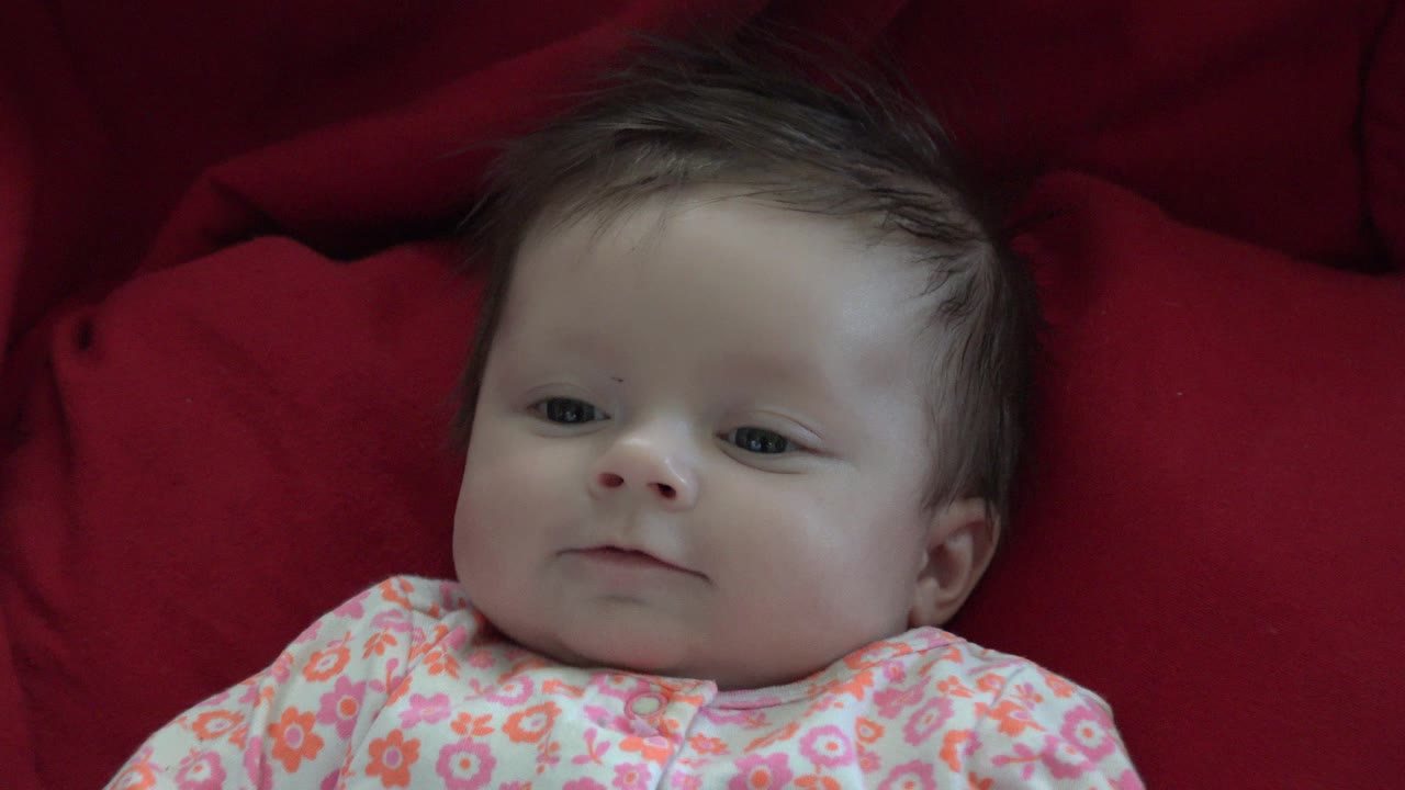 Close view of baby on red fabric looking upward.