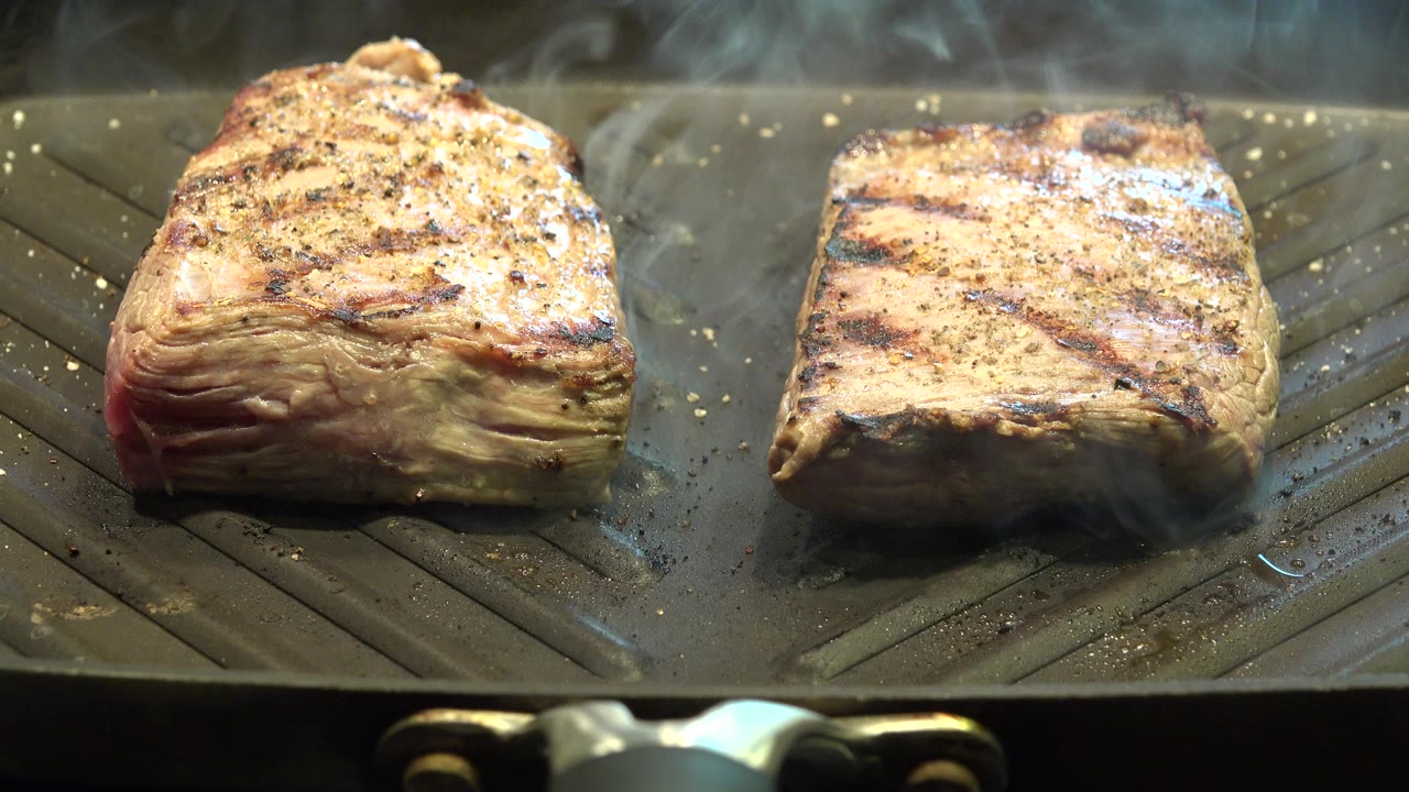 Two thick chicken slabs on a smoking ridged grill
