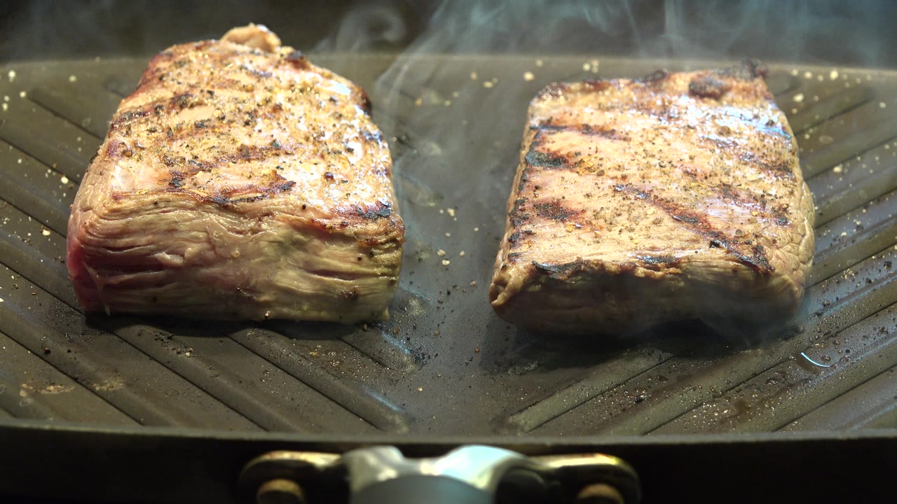 The chicken remains centered on the grill pan, with char lines across the top and light smoke drifting behind it in Westminster, Colorado.