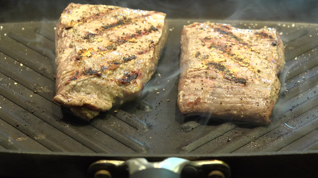 At 0:00, two browned pieces of meat cook on a ridged grill pan in Westminster, Colorado, with light smoke rising and no visible people.