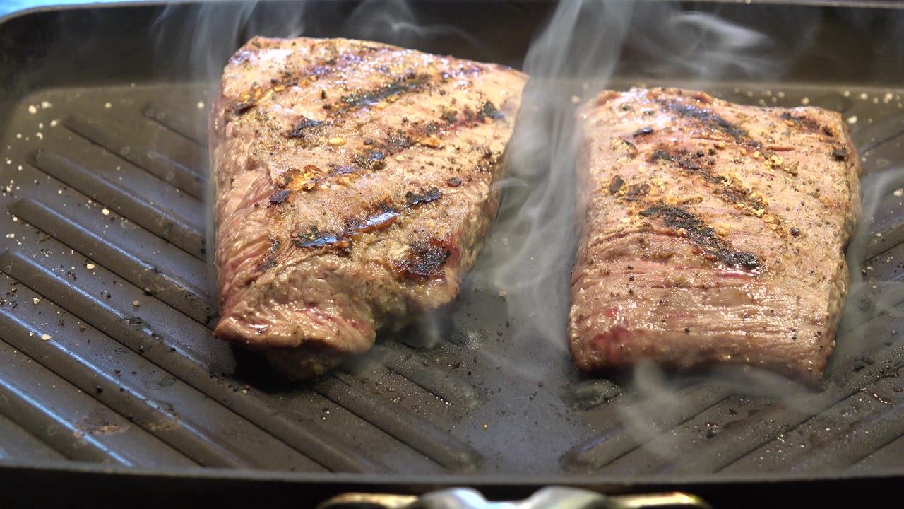 The steaks remain on the indoor grill pan in Westminster, Colorado, with smoke moving across the top of the frame and no visible people.
