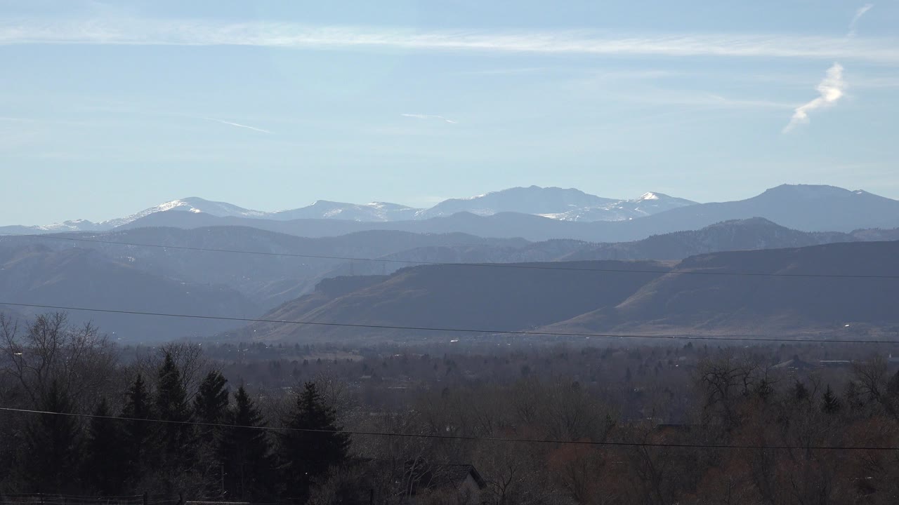 Distant snow-capped mountains beyond dark trees and low hills.