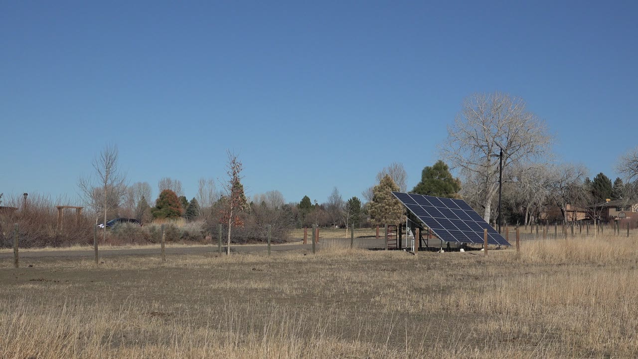 Large solar panel in a dry winter field under a clear blue sky.