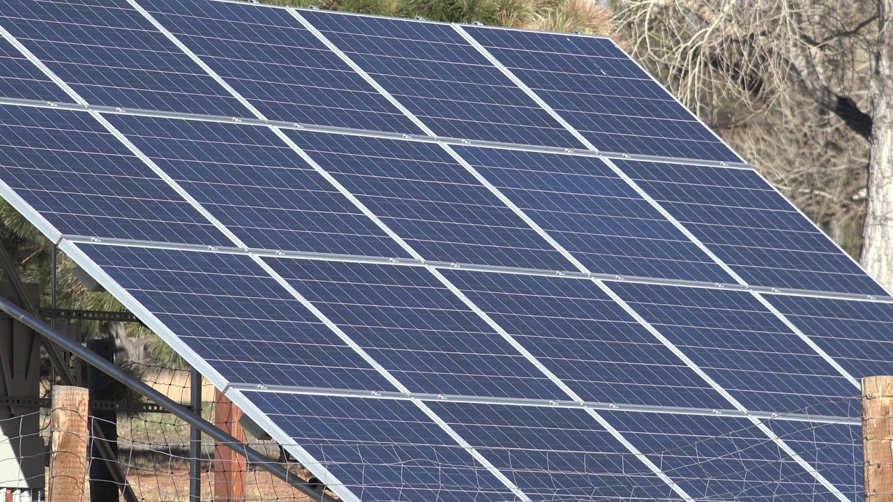 Large solar panels seen close up with a wooden post at the right edge.