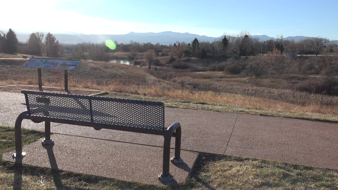 Park bench beside a path with mountains in the distance