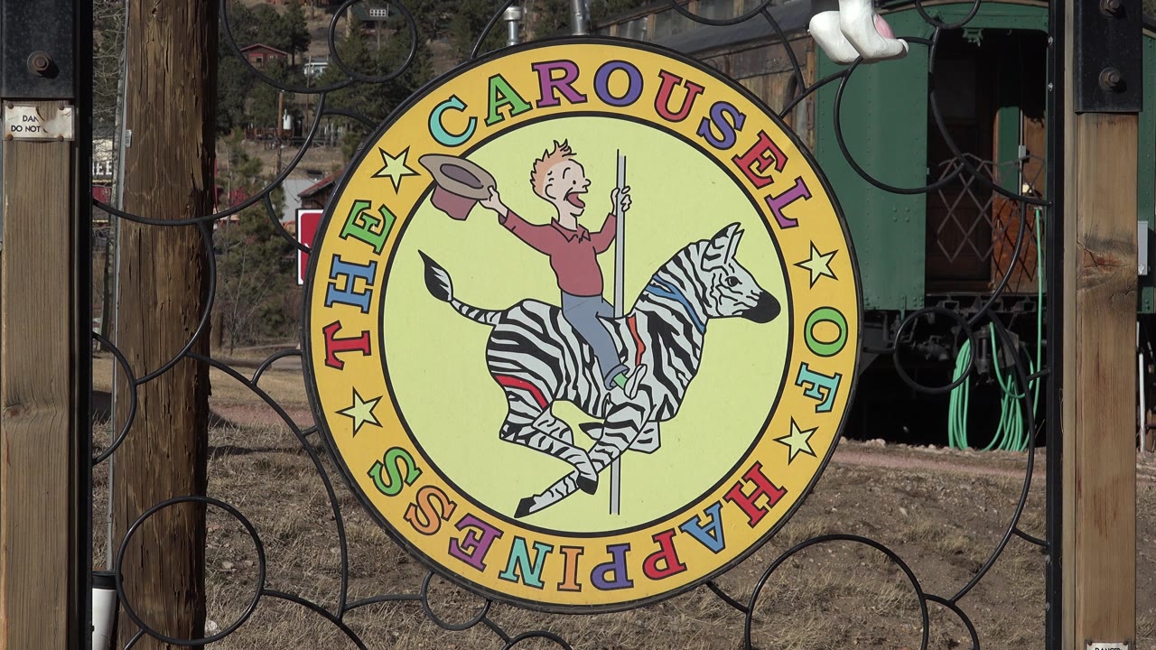 Yellow carousel sign with zebra graphic at outdoor gate.