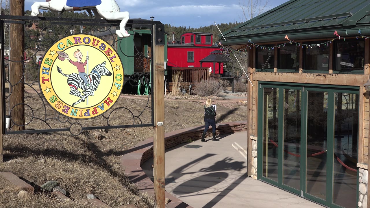 Woman and child near the right side of the path at a carousel entrance.
