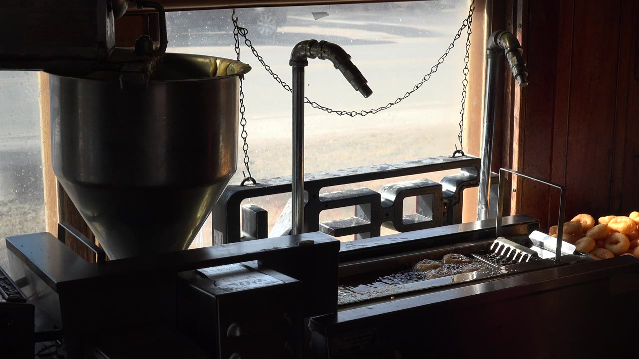 Backlit fryer station beside a window with trays of fried food.
