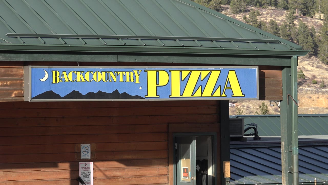 Backcountry Pizza sign above a wood storefront and doorway.