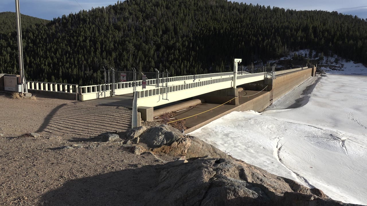 Concrete dam wall and white bridge at a frozen lake