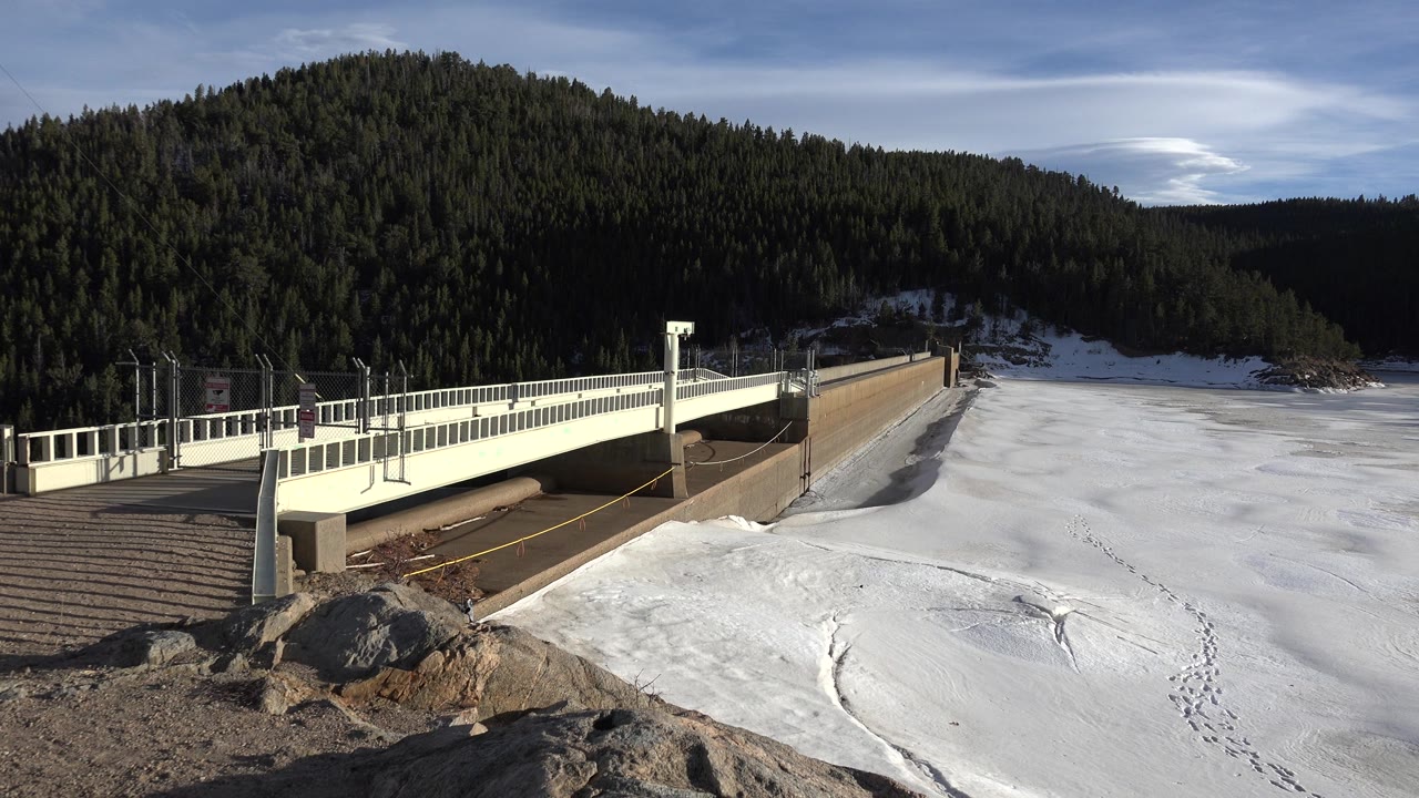 Bridge railing above snow with mountain forest background