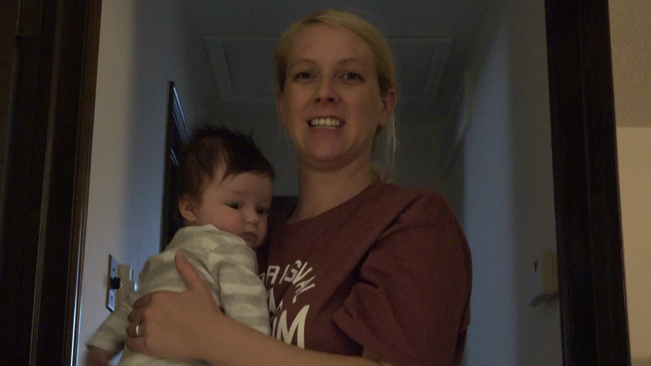 Woman holding a newborn in a dim hallway