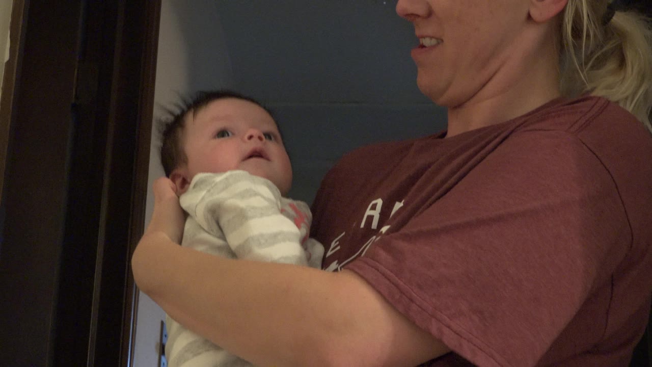 Woman smiling slightly while holding a baby.
