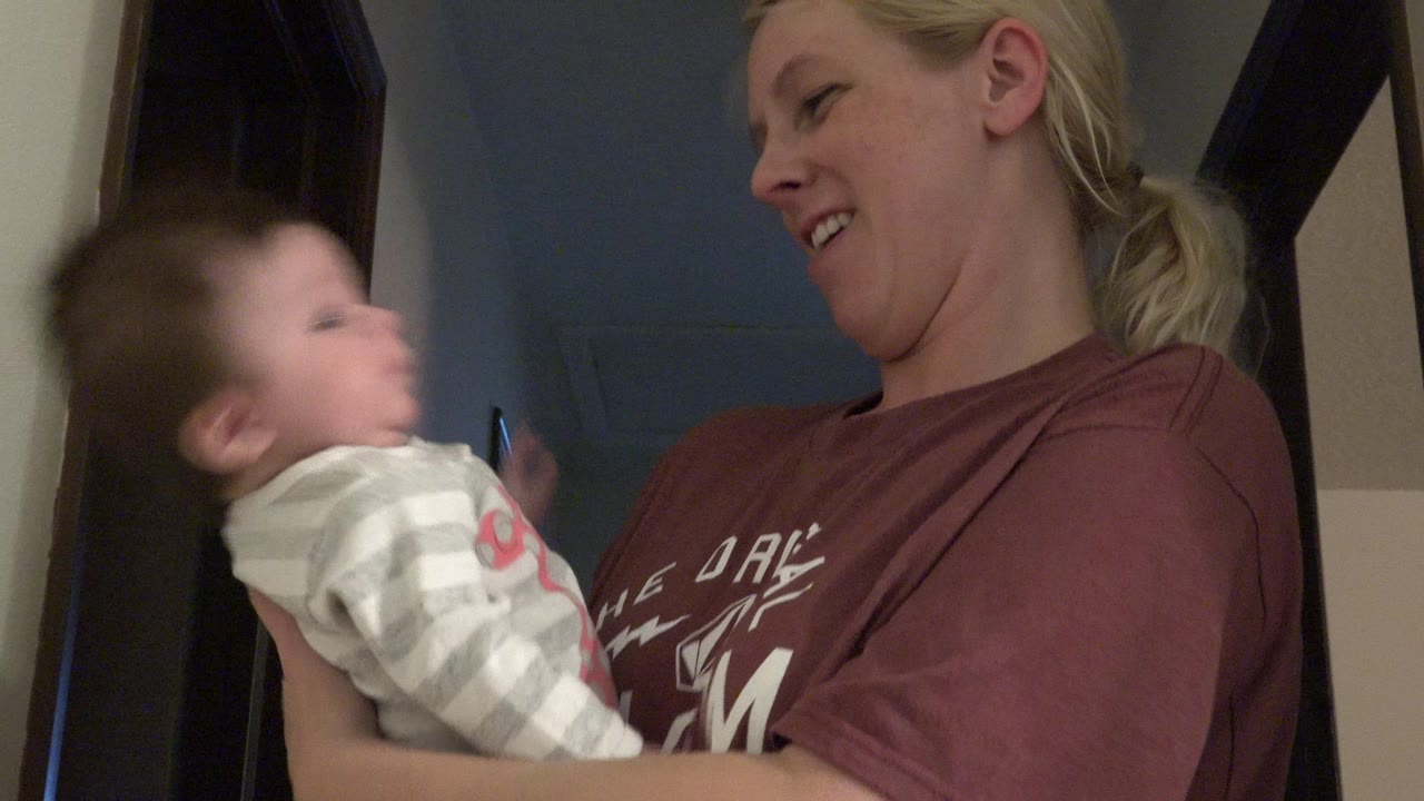 In Westminster, Colorado, the mother remains close to the baby as the infant turns with motion blur against a hallway doorway.