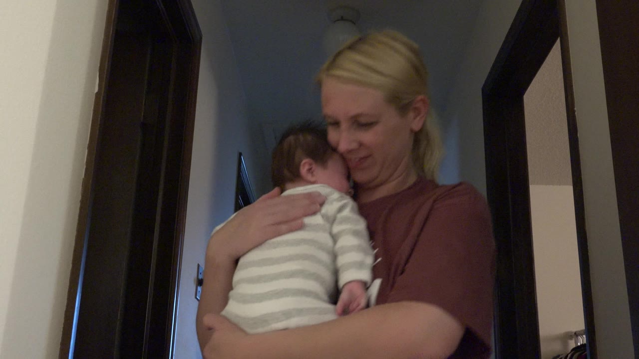 Mother cradles the baby higher against her chest.