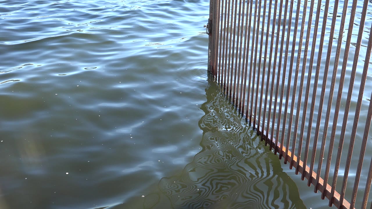 Opening frame of rippling water in Westminster, Colorado, with a vertical slatted structure entering from the right and no visible people.