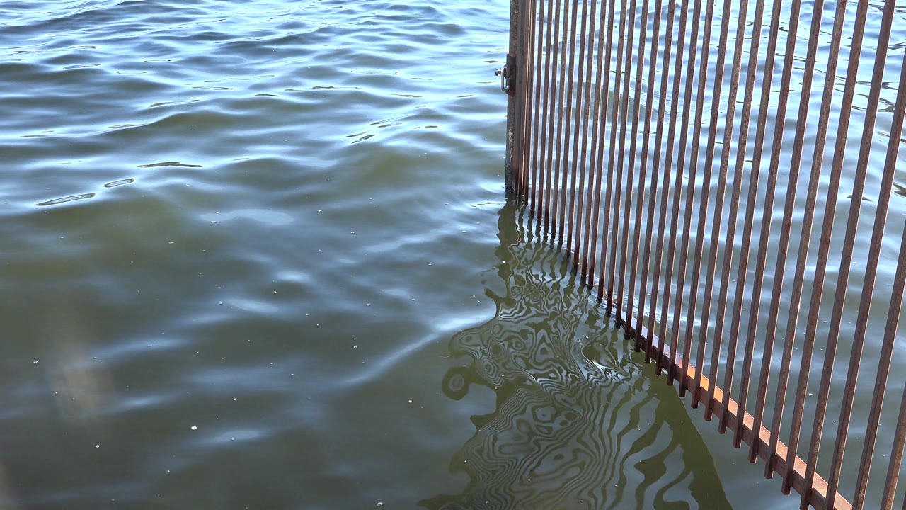 Slatted structure reflected in moving water.