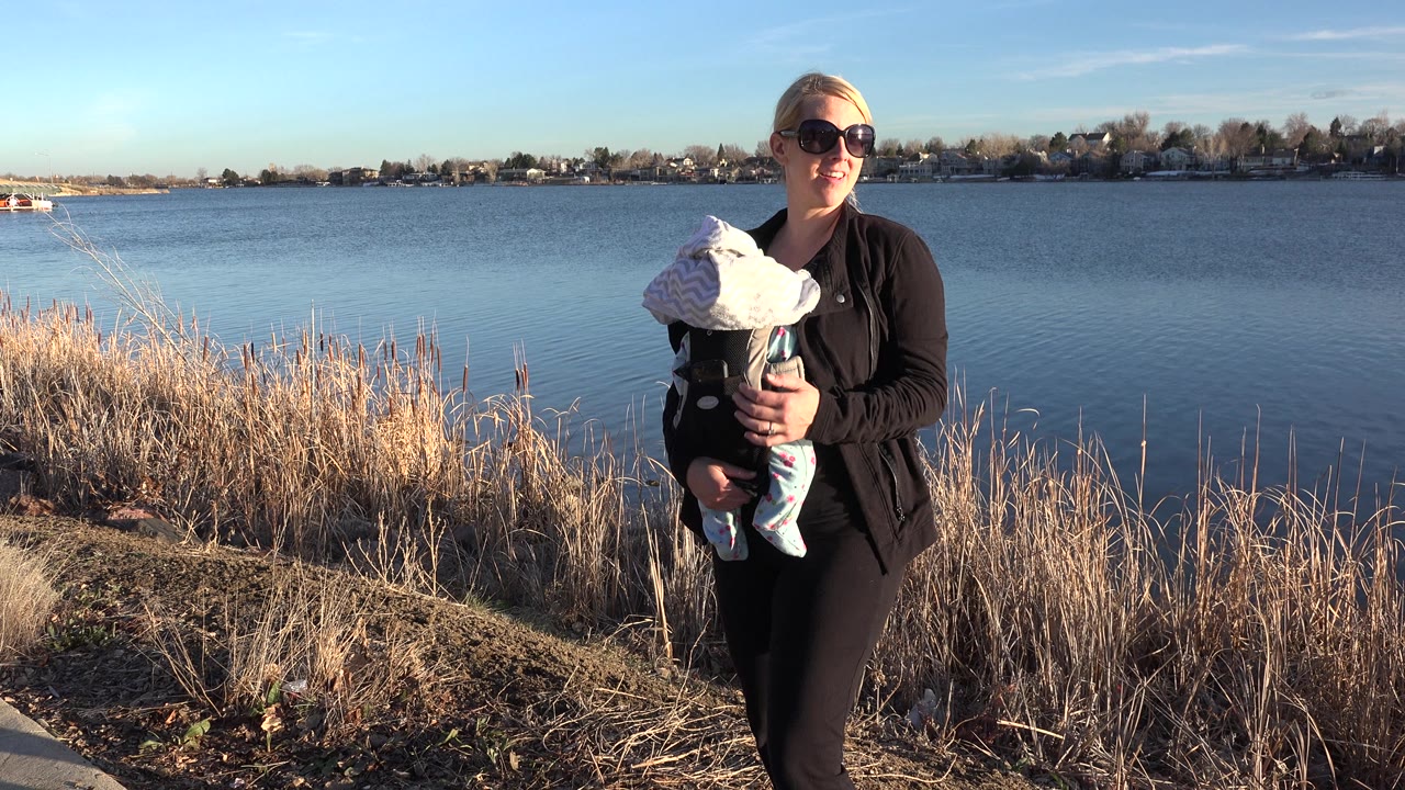 Woman holding child while standing at the edge of a lake.