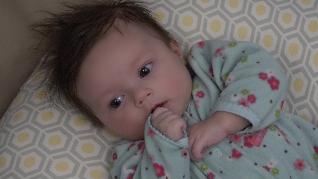 Baby in floral blue sleeper looking slightly aside.