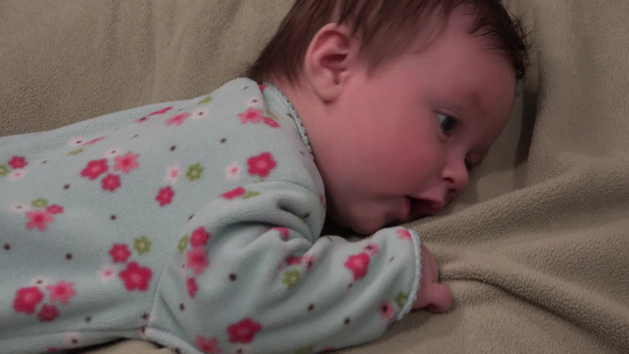 Baby looking to the side while lying on a soft blanket.