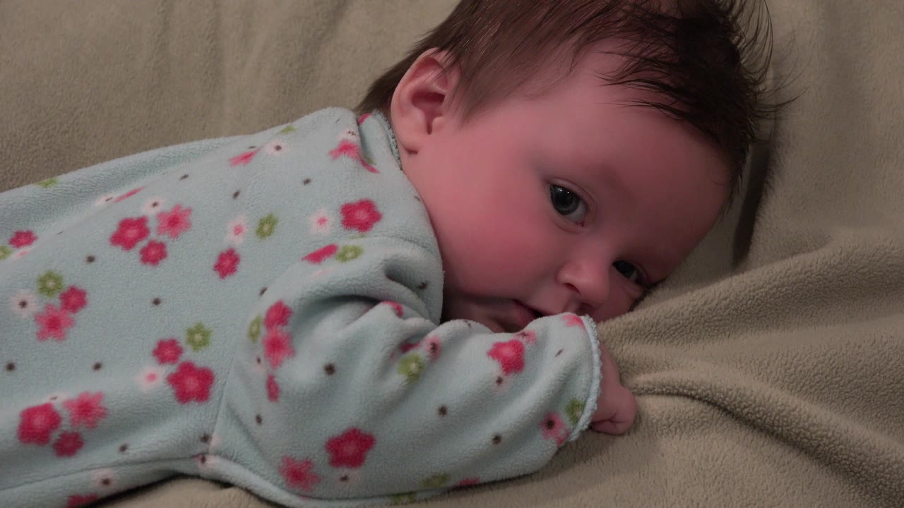 Baby lying on her stomach on a light blanket.