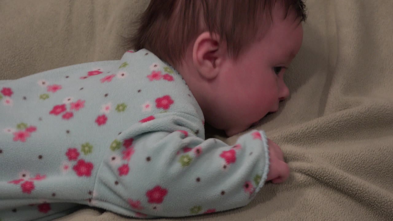 Baby girl lying on her stomach on a beige blanket