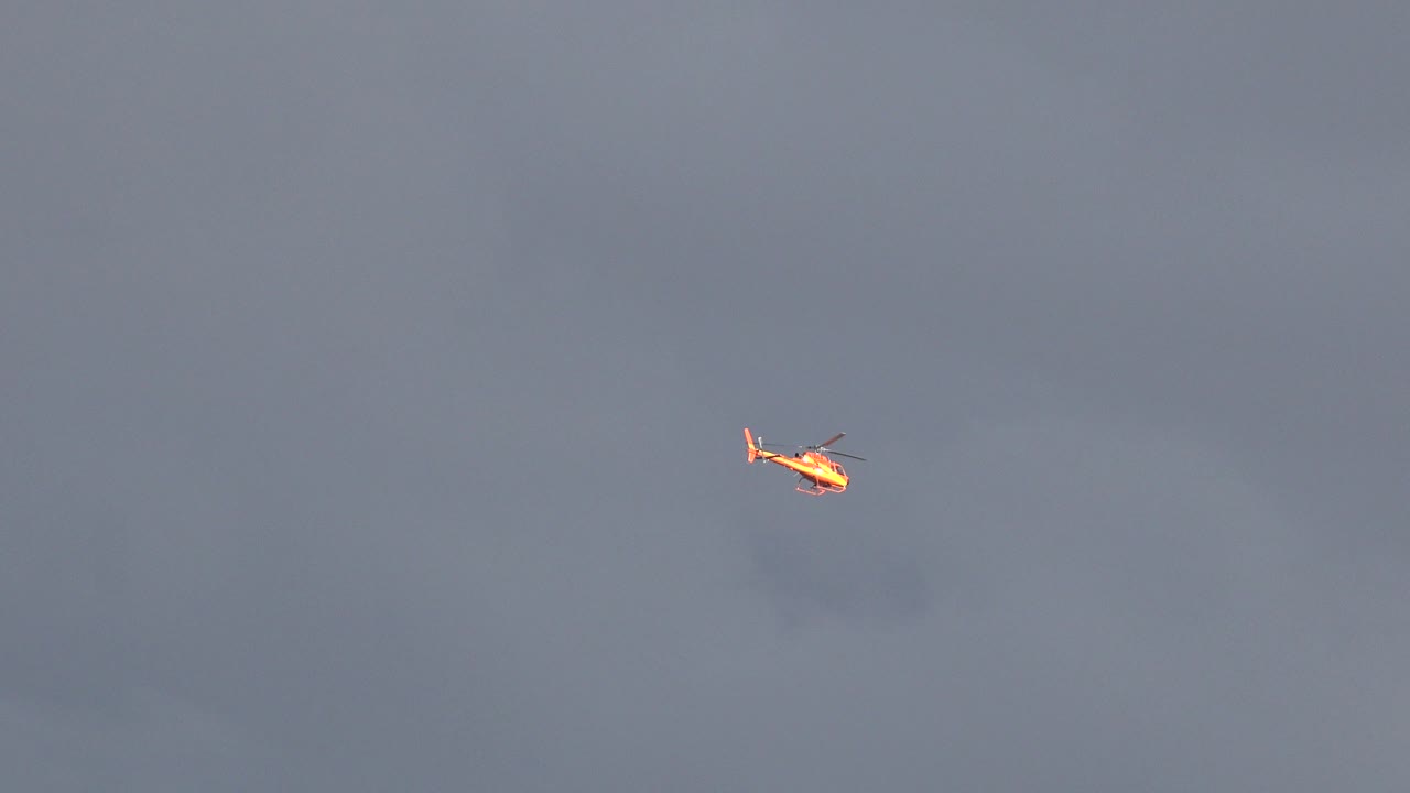 Small red and white helicopter near the upper left of a cloudy Westminster, Colorado sky, with no visible people.