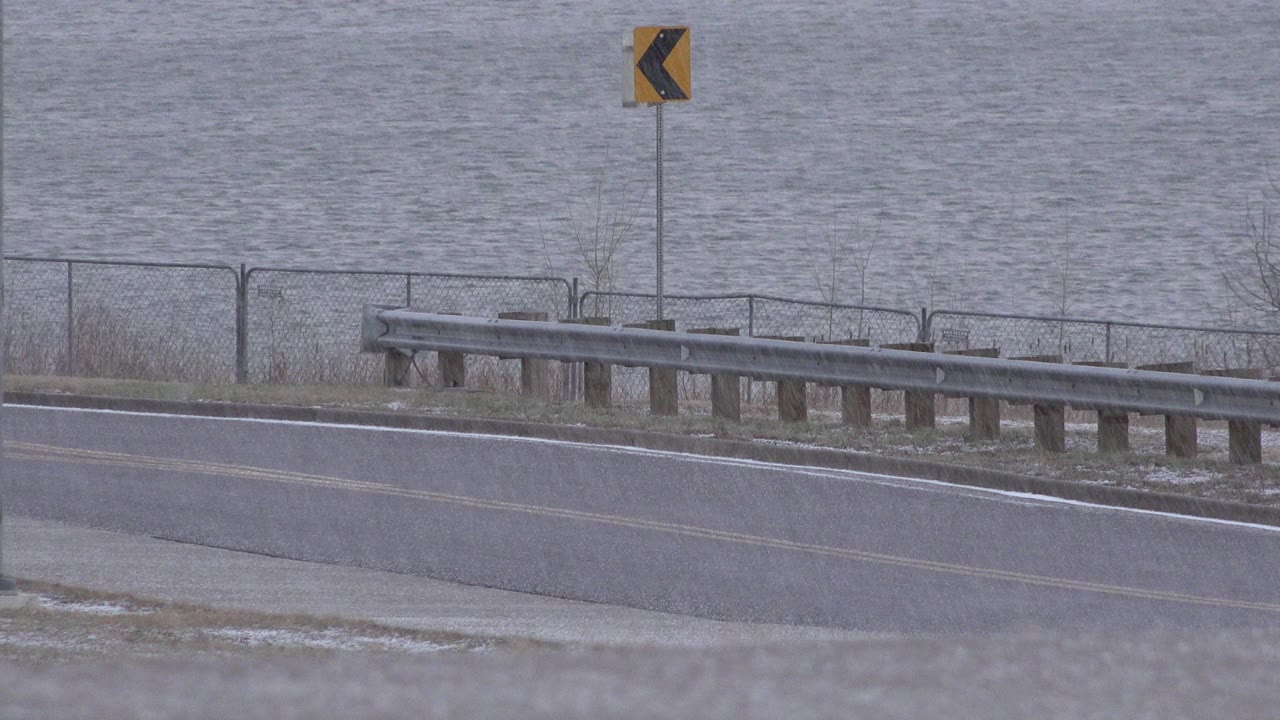 Curving roadside with guardrail and water behind it