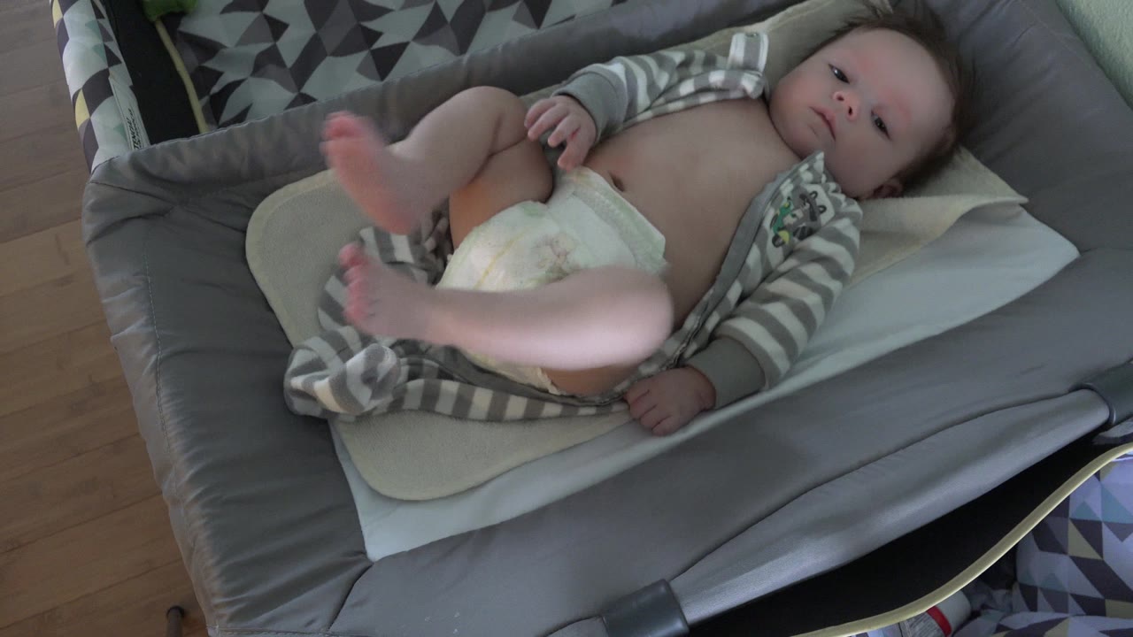 Infant lying on a changing pad with legs raised.