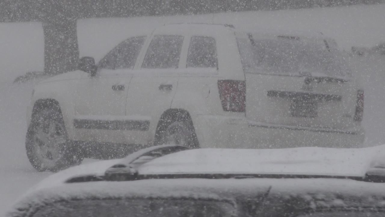 At 0:00, a white SUV is seen through heavy falling snow in Westminster, Colorado, with a snow-covered vehicle roof in the foreground and no visible people.