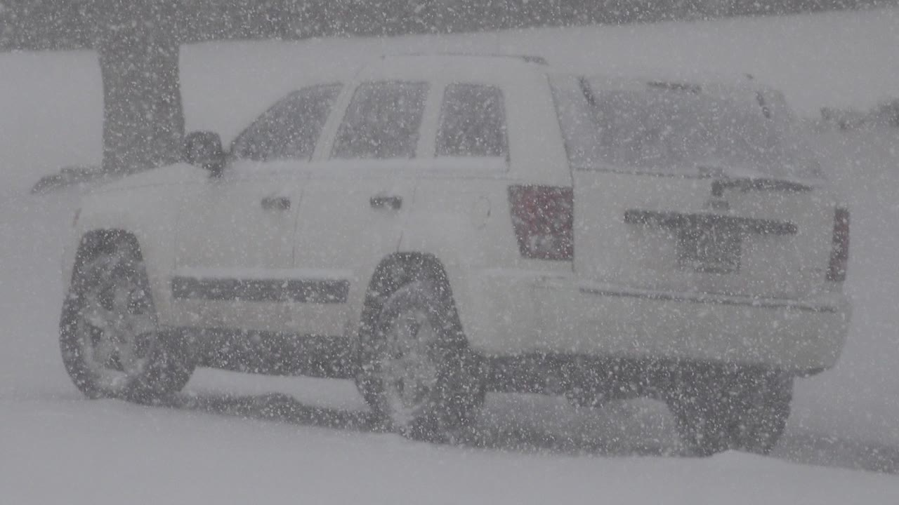 White SUV parked in heavy blowing snow.