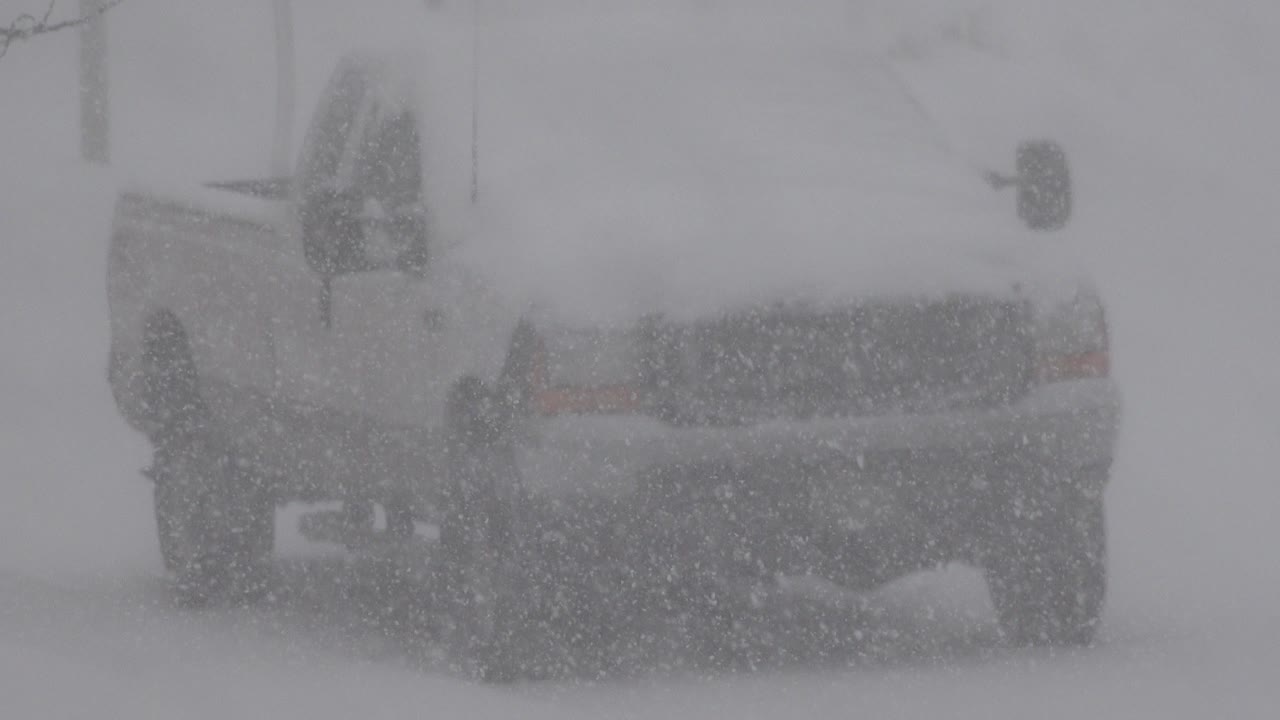 Snow-covered car seen through heavy falling snow.