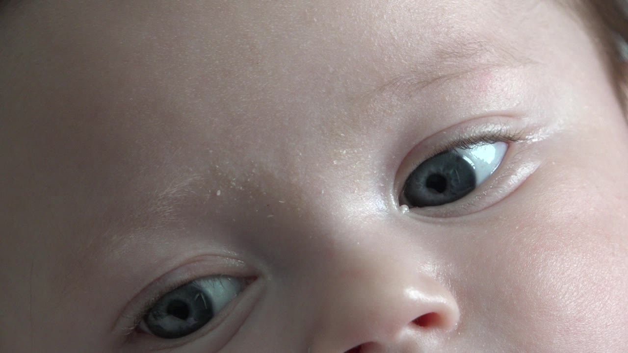 At 0:01, the infant's face remains tightly cropped in Westminster, Colorado, with one blue eye prominent and the other partly visible near the lower edge.