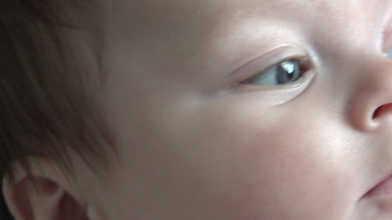 Partial close-up of a baby's eye, cheek, nose, and red hair.