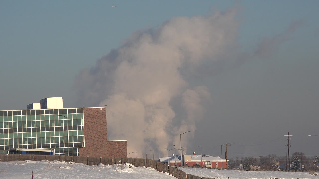 Snowy industrial roadside view with smoke or steam plume