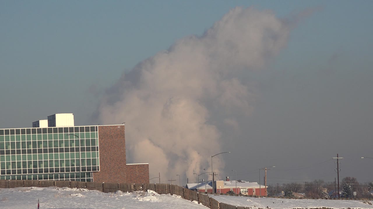 Smoke drifting upward over industrial buildings