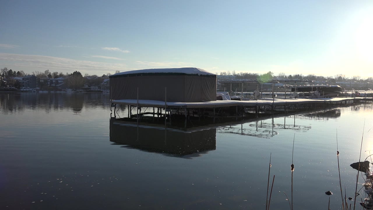 Covered dock over a calm lake in bright sun.