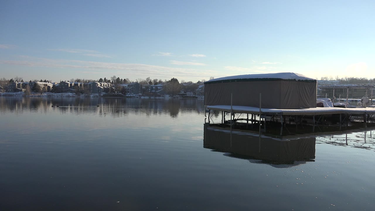 Tan covered platform over calm water with distant houses