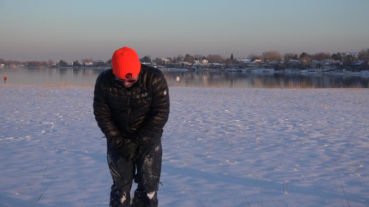 Man bends forward while standing up from the snow.