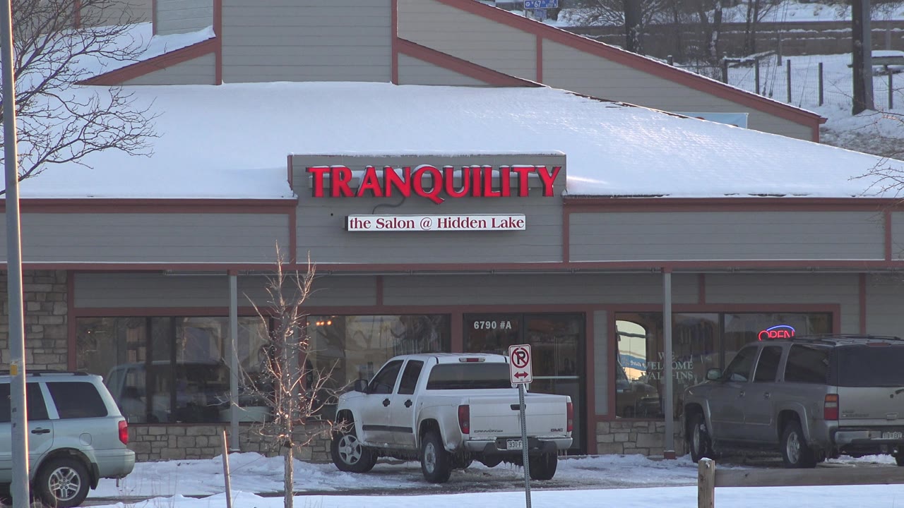 The salon exterior remains centered in Westminster, Colorado, with snow along the roofline, two parked trucks, reflective storefront glass, and no visible people.