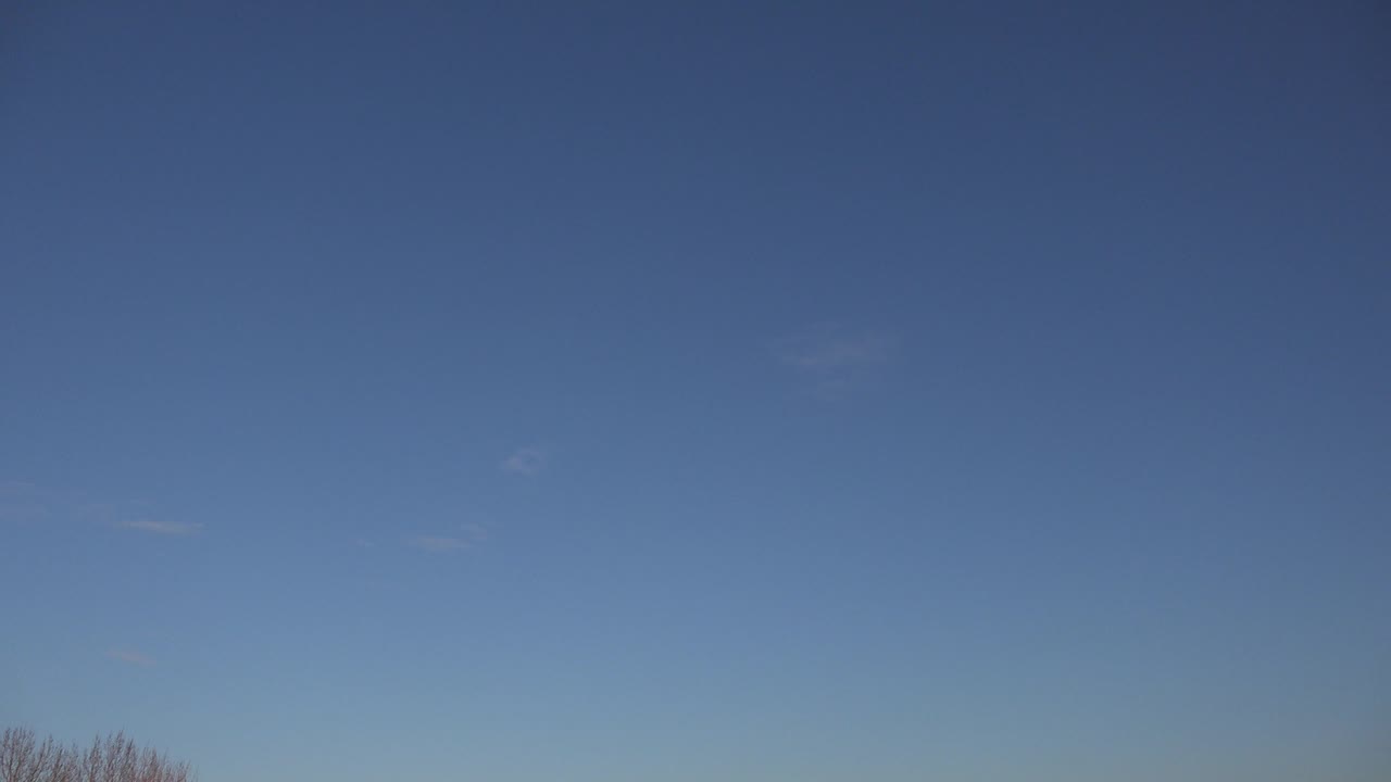 Open blue sky with a small line of bare trees near the bottom.
