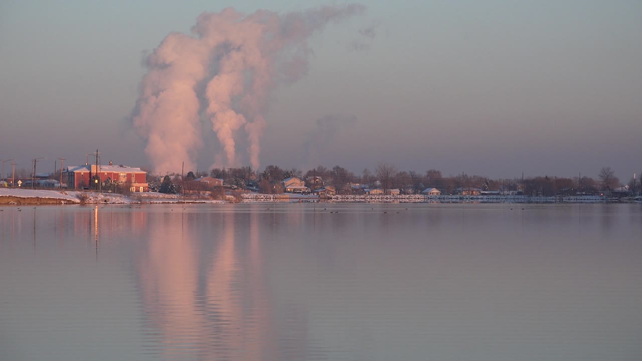 At one second, the Westminster waterfront remains wide and steady, with pink light on the distant plume or cloud and soft reflections below, with no visible people.