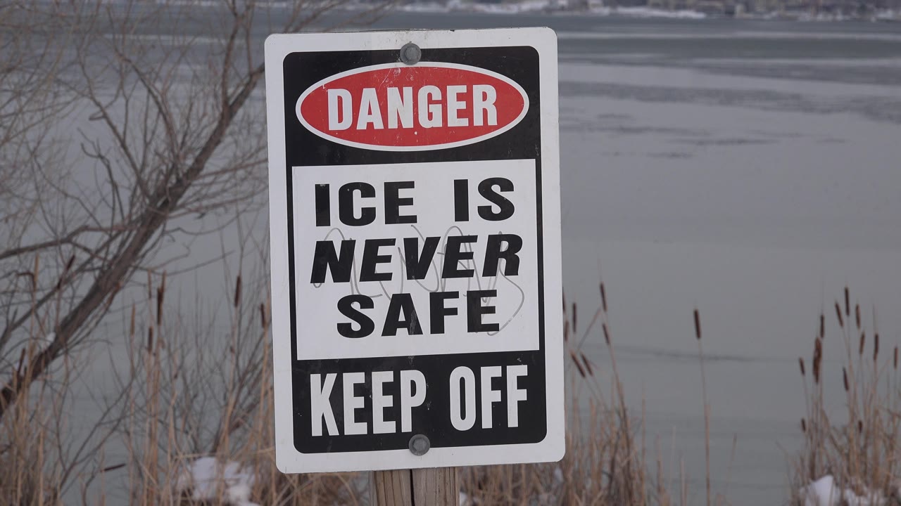 Danger ice sign in front of a gray lake and winter vegetation.