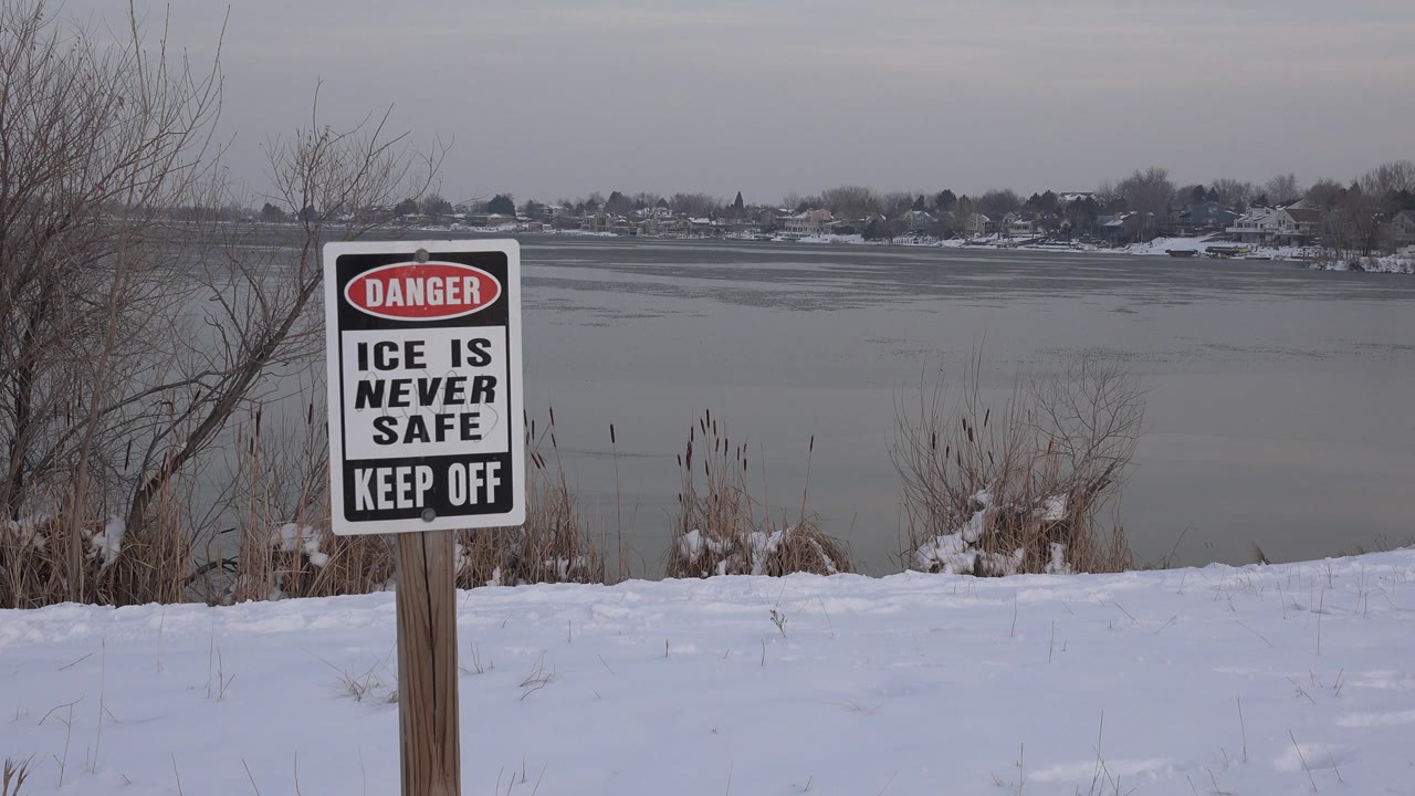 Danger sign beside a snowy frozen lake