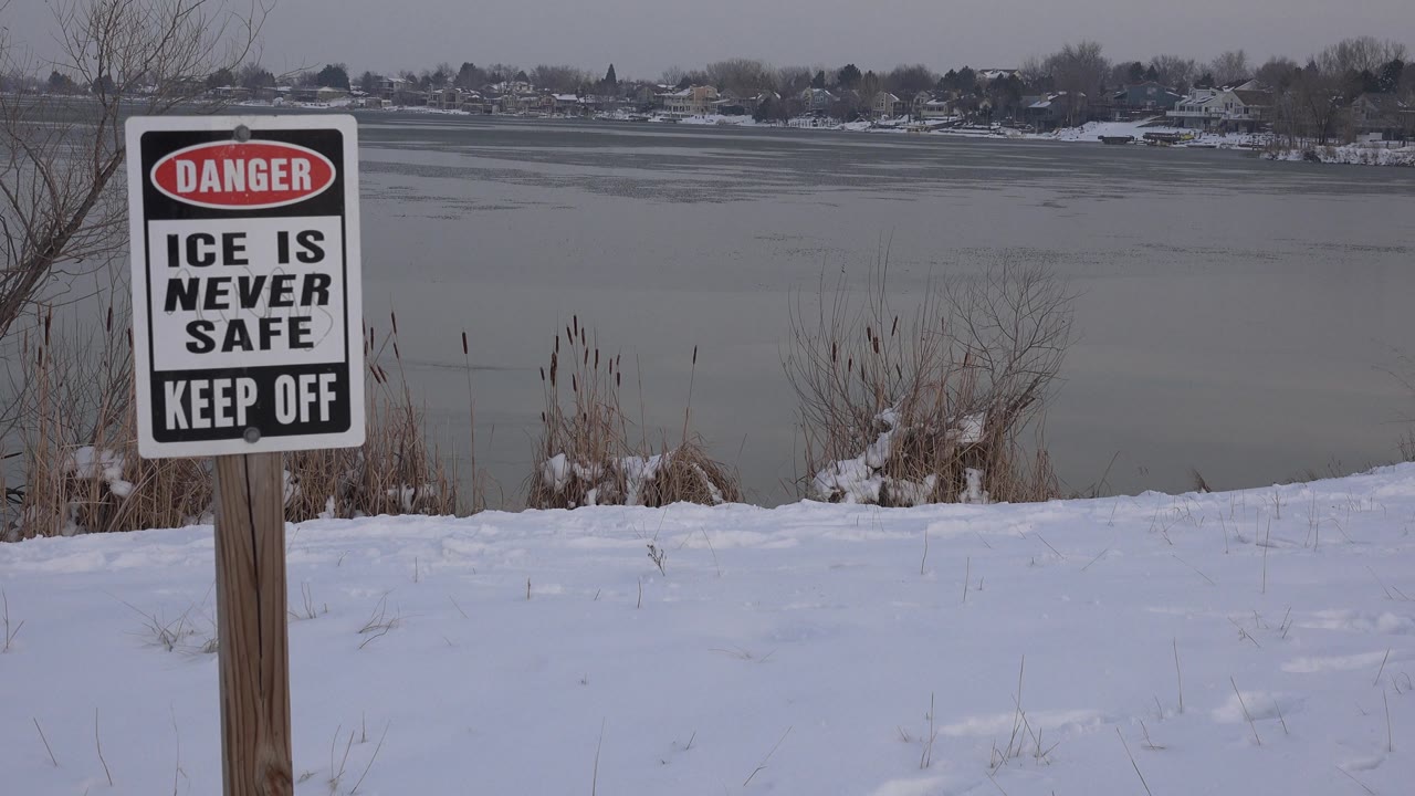 Warning sign centered against snowy bank and frozen lake