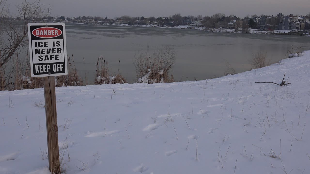 Danger sign posted near snow and icy water.