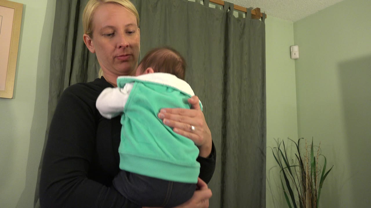 Woman looking down while holding a baby indoors.