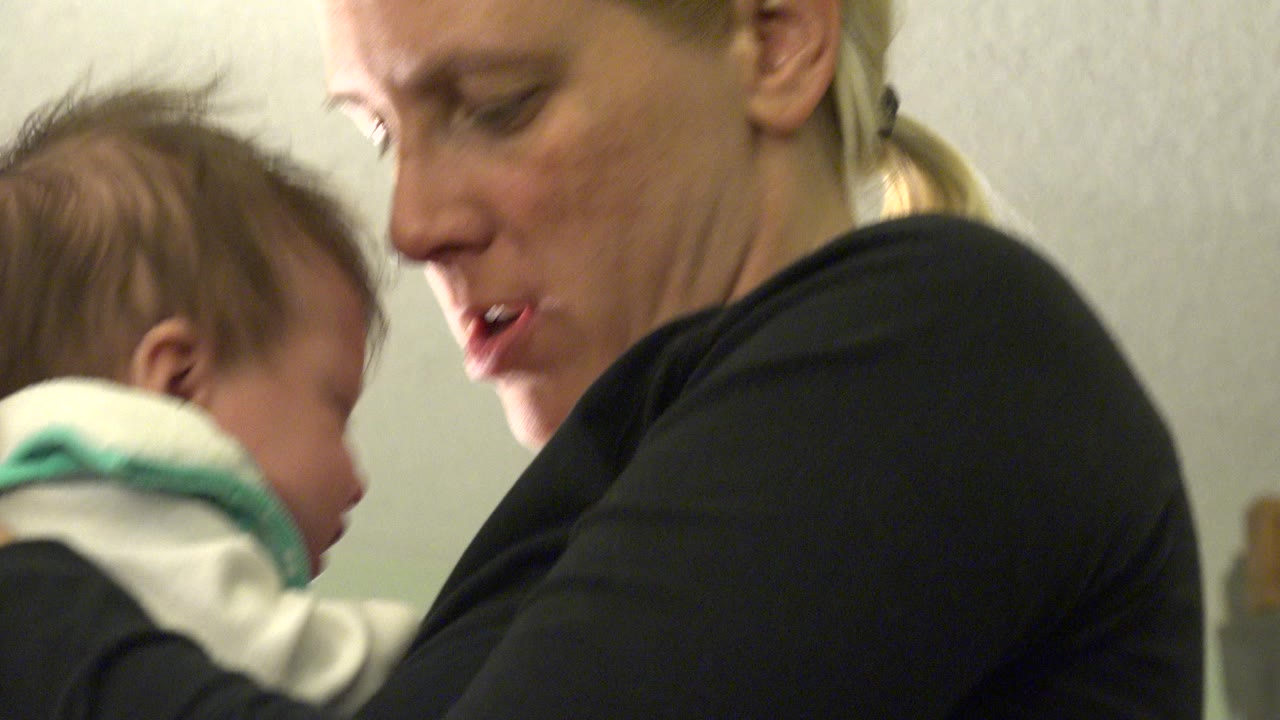 Mother holding a crying baby in a tight indoor close-up.